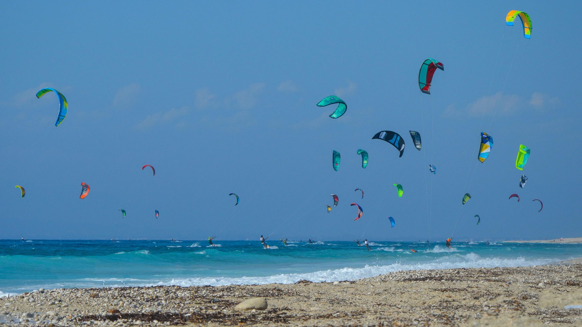 Escena dinámica con varios practicantes de kitesurf en Grecia, que captura la esencia de la aventura y los deportes al aire libre.